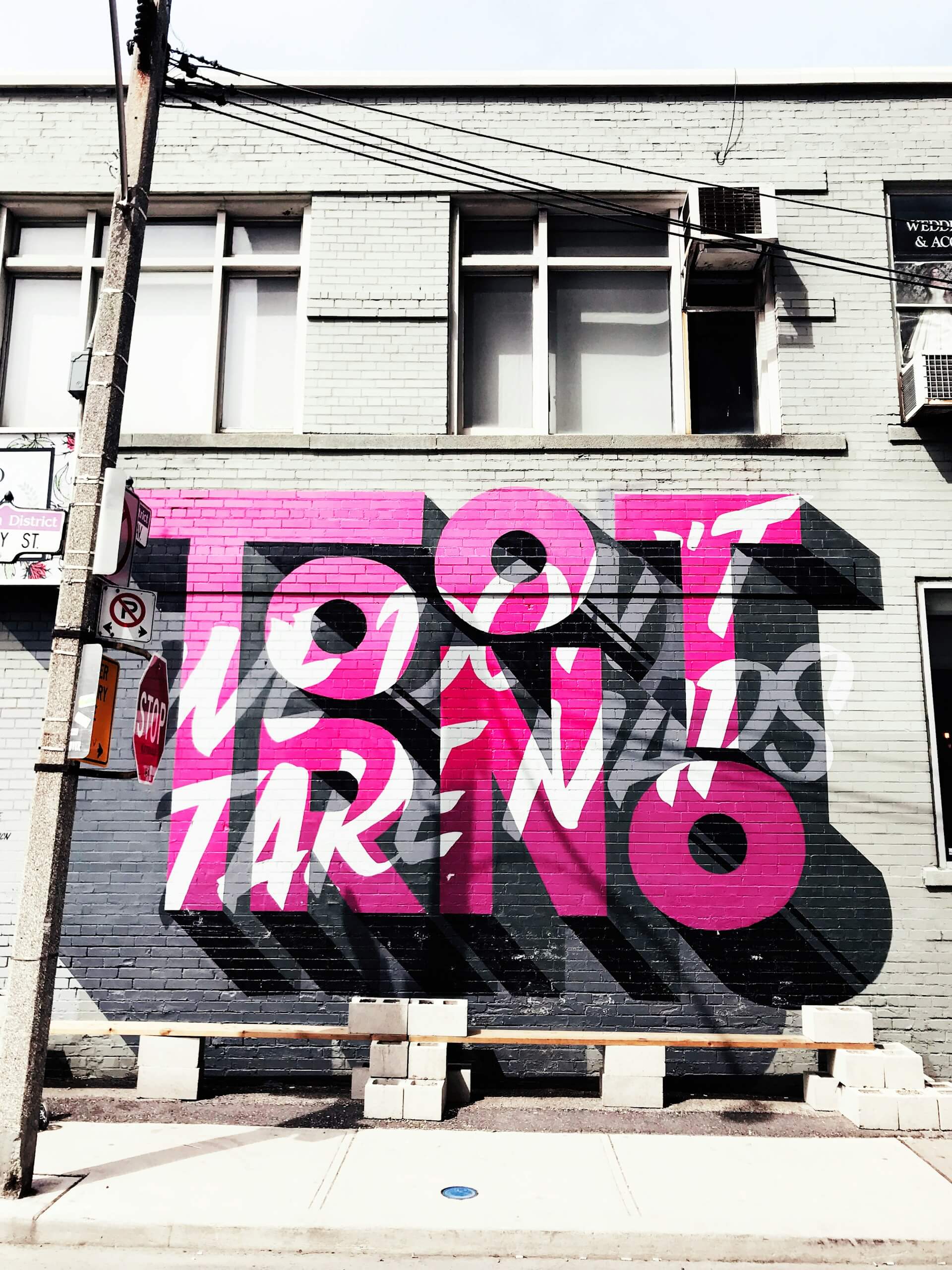 A large pink and black mural on the side of a building writing Toronto